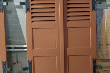 Photo d'une paire de volets en bois qui vient d'être repeinte et dont les ferrures métalliques avec gonds ont été remontés.